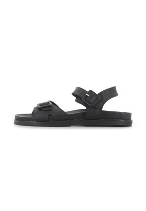Sandalias negras de cuero con suela plana. Cuentan con dos correas ajustables y un detalle de hebilla cuadrada. Diseño simple, de dedos al aire.