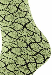 Grüne Socke mit einem schwarzen Blumenmuster, das große blattähnliche Formen und feine Details aufweist, aus weichem, dehnbarem Stoff gefertigt.