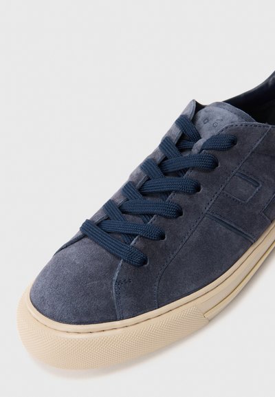 Blue suede sneaker with cream rubber sole and matching blue laces, shown at an angle on white background.