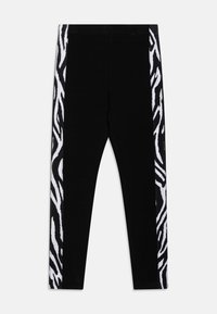 Leggings noirs avec un devant uni, présentant des panneaux à rayures zèbres blanches sur les deux côtés. Texture lisse et design ajusté.