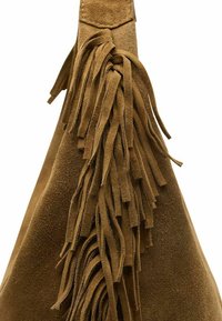 Bruine suède handtas met lange, getextureerde franjes aan één kant, met een gladde afwerking en een driehoekige vorm aan de bovenkant.