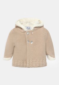 Beige stickad kappa med en foder av päls i huvan. Har ett flätat mönster vid nederkanten och två iriserande knappar för stängning.