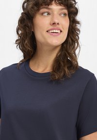 Marineblaue Baumwoll-T-Shirt mit einem klassischen Rundhalsausschnitt und kurzen Ärmeln. Glatte Textur ohne sichtbare Muster oder Verzierungen.