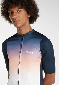 Cyklistický dres s krátkym rukávom má gradient od námorníckej modrej po svetloružovú, zips na prednej strane a biele logo "Protest Cycling" na hrudi.