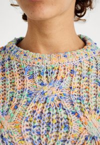 Bunter gestrickter Pullover mit filigranen Mustern in Pastellfarben wie Pink, Blau, Grün und Orange. Rundhalsausschnitt mit strukturierten Details.