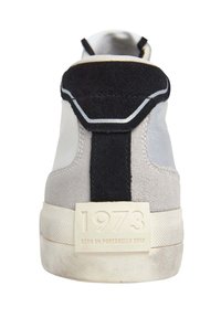 Hohe Sneaker aus grauem Wildleder und Leder, mit einem schwarzen Akzentriemen, weißer Sohle und geprägtem "1973"-Detail an der Ferse.
