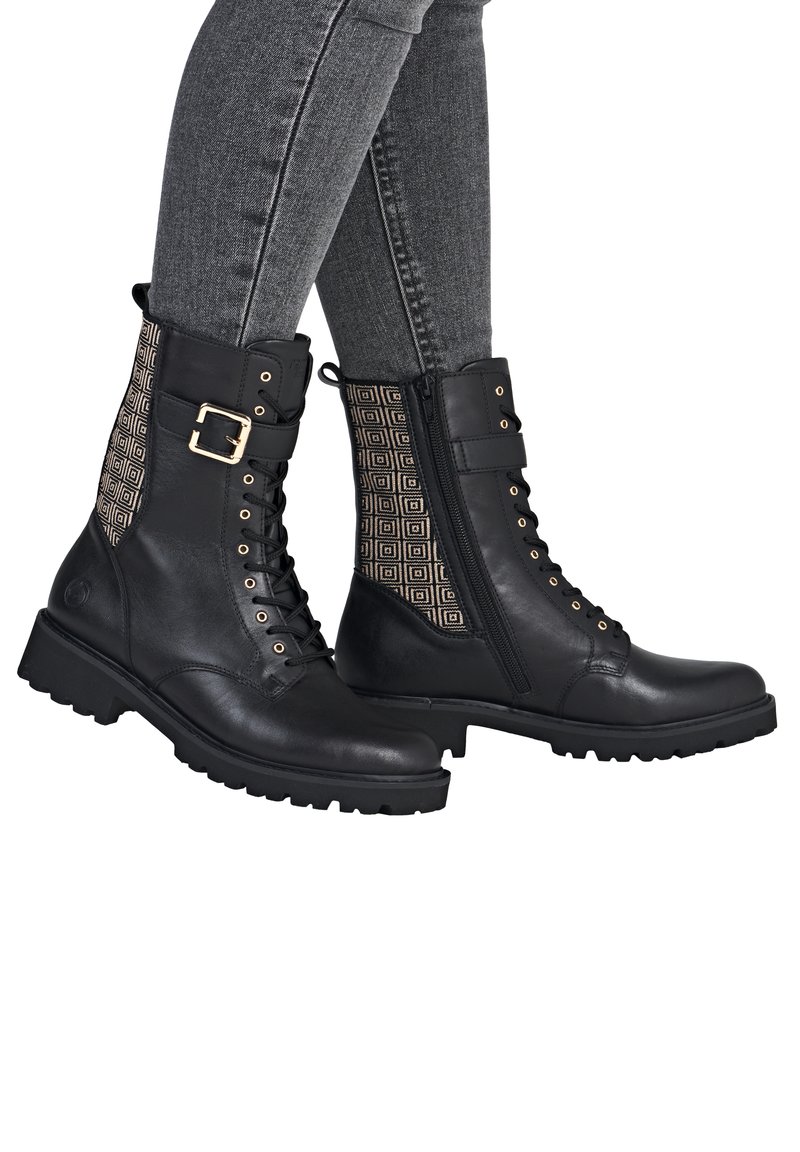 Bottines en cuir noir avec un panneau en textile à motifs, des accessoires dorés, un laçage à l'avant et une fermeture éclair sur le côté, dotées d'une semelle en caoutchouc épaisse.