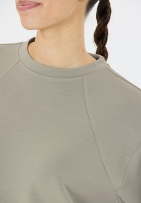 Lichtgrijze, zacht aanvoelende sweatshirt met een ronde hals en raglanmouwen. Heeft gladde naden en een relaxte pasvorm.