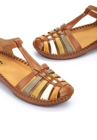 Sandalias de cuero marrón con diseño tejido a rayas en dorado, verde y marrón. Presenta una correa en T y detalles de costura en la suela.