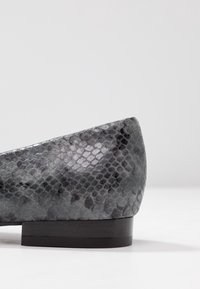 Płaskie buty wykonane z szarego materiału w motyw węża, z zaokrąglonym czubkiem i niskim czarnym obcasem. Gładka tekstura z połyskującym wykończeniem.