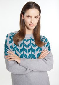 Pulover gri deschis cu un model de frunze turcoaz, gât rotund și mâneci lungi, având o textură moale și o croială lejeră.