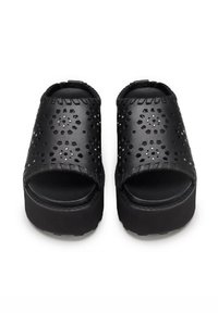 Sandali platform neri senza laccio con motivo floreale ritagliato, superficie testurizzata e suole in gomma spesse. Presentano bordi intrecciati e punta aperta.