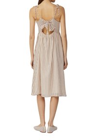 Gestreiftes Midikleid mit offener Rückseite, gebundenem Schleifendetail und verstellbaren Spaghettiträgern. Leichter Stoff in Beige- und Staubrosa-Tönen.