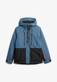 Niebieska i czarna kurtka z kapturem, z zamykanymi na zamek kieszeniami oraz wyraźnym logo "SUPERDRY". Gładka tekstura, sportowy design.