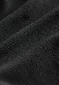 Svart tyg med en texturerad väv, med subtil lyster och veck som framhäver materialets flexibilitet och mjukhet.
