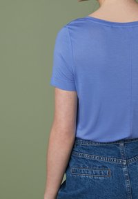 Korte mouwen lichtblauw T-shirt van zachte stof, met een ronde halslijn en een ontspannen pasvorm, gecombineerd met high-waisted denim shorts.