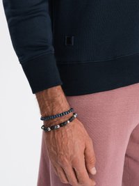 Marine sweatshirt met geribbelde manchetten, gecombineerd met roze gestructureerde broeken. Drie kraalarmbanden in verschillende kleuren, texturen en maten sieren de pols.