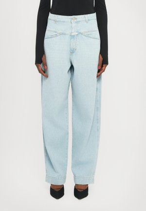 Light blue high-waisted jeans with a loose fit, featuring front pockets, light stitching, and a button closure. Worn with black heels.