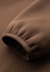 Brunt texturerad tyg med ett fint rutmönster, med puffärmsdetalj. Mjuk material med en slät yta.
