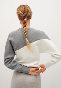 Light gray and white sweatshirt featuring a diagonal color block design, round neckline, and ribbed cuffs, made from a soft, textured material.