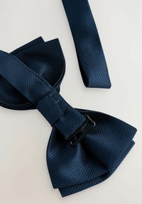 Pajarita azul marino hecha de tela texturizada, con una hebilla negra y un acabado liso, con una forma clásica y extremos superpuestos.