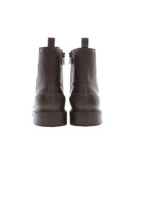 Botas de tobillo de cuero marrón con una textura suave, que cuentan con un tacón bajo en bloque, cremalleras laterales y detalles de costura en la parte trasera.