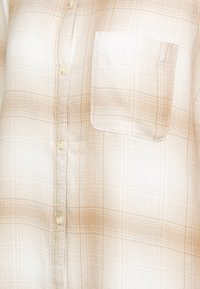 Camicia a maniche lunghe a quadri beige chiaro con taschino, realizzata in un tessuto morbido e con un motivo a scacchi sottile in tonalità più chiare e scure.