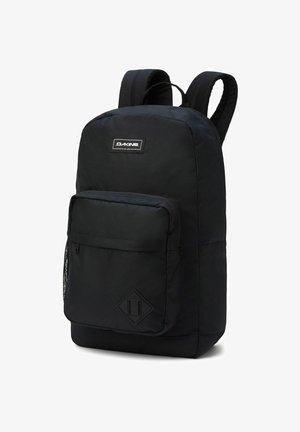 Black backpack made of durable fabric, featuring a main compartment and a front pocket, padded straps, and a diamond-shaped accent on the bottom.