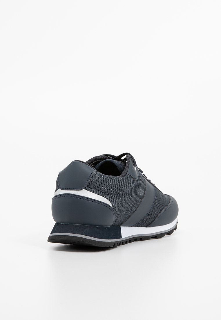 Dunkelblaue sportive Sneaker mit weißer und grauer Sohle, Obermaterial aus Mesh und Synthetik, von hinten auf weißem Hintergrund gezeigt.