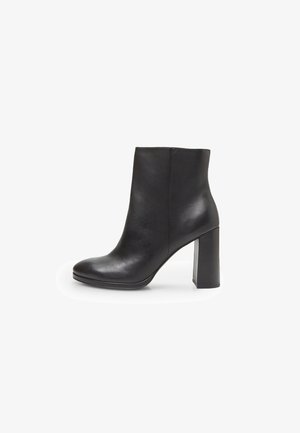 Bottine en cuir noir avec un bout rond et un talon carré de hauteur moyenne. Texture lisse avec un minimum de détails de couture.