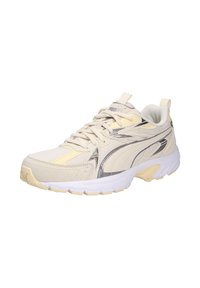 Beige athletic shoe with a mix of leather and mesh materials. Features metallic silver accents, white and yellow sole, and textured patterns.