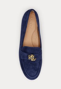 Mocassim em camurça azul marinho com sola plana, apresentando um detalhe com o logótipo em ouro "RL" na tira e uma palmilha almofadada com perfurações.