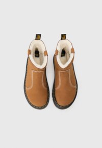 Botine din suede maro, cu interior din blană sintetică albă, talpă din cauciuc negru, cusături galbene și mânere la călcâi. Design cu vârf rotund și plat.