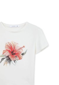 T-shirt bianco in cotone con un grande design di fiore hibiscus rosso con foglie verdi, maniche corte e scollatura rotonda. Etichetta della taglia visibile.
