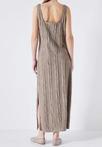Robe maxi en tricot beige avec une texture en côtes verticales, bretelles larges et fentes sur les côtés. Le dos présente un décolleté carré.