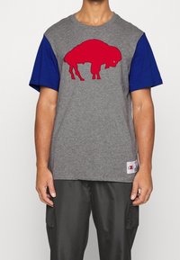 Grå t-shirt med korte blå ærmer, der har et rødt bison-tryk på forsiden. Etiketten nederst inkluderer logo og plejeoplysninger.