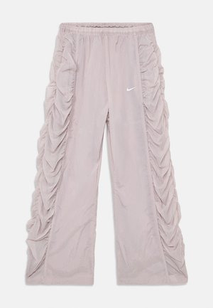 Lyse rosa Nike-bukser med rynket tekstur langs sidene; elastisk midje og logo øverst til venstre på forsiden.