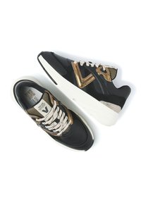 Schwarze und goldene Turnschuhe mit Mesh- und Wildlederpaneelen, cremefarbenen Schnürsenkeln und dicken weißen Sohlen, die ein auffälliges Logo an der Seite haben.