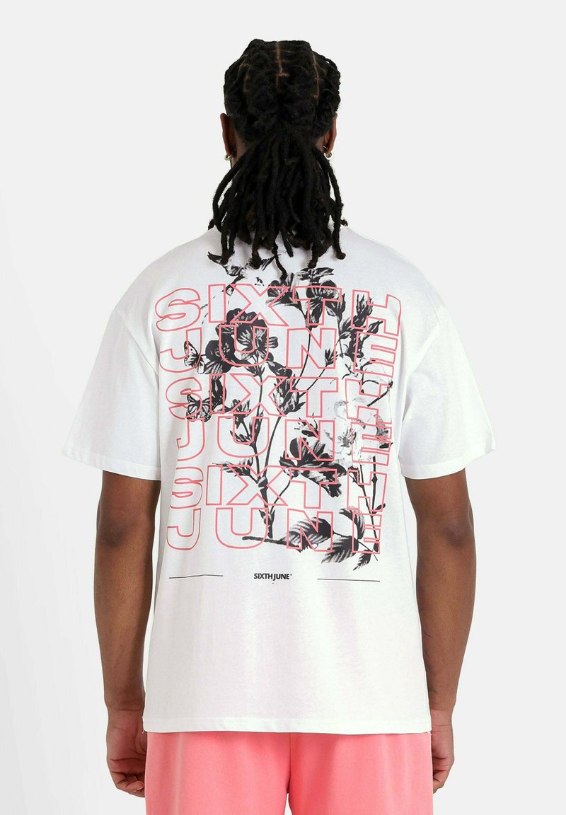 Wit katoenen T-shirt met opvallende zwarte en roze tekst "SIXTH JUNE" over een bloemmotief. Korte mouwen, losse pasvorm.