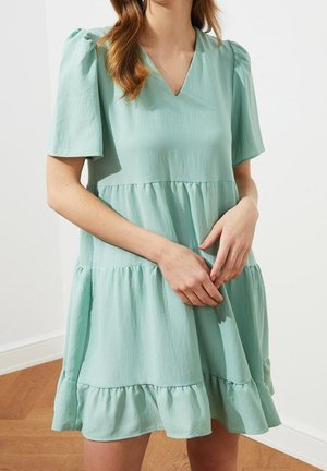 Miętowa sukienka z krótkimi bufkami, dekoltem w serek i warstwowym falbanym dołem. Wykonana z lekkiego materiału o miękkiej fakturze.