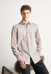 Camicia chiara con colletto classico in un motivo geometrico, realizzata in un tessuto testurizzato, con bottoni scuri.