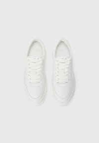 Et par hvite skinn sneakers med snøring og perforerte detaljer, sett ovenfra på en enkel hvit bakgrunn.