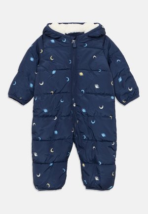 Combinaison de neige bébé bleu marine avec capuche, fermeture éclair devant, et petits motifs lune et planète en bleu, jaune et blanc.