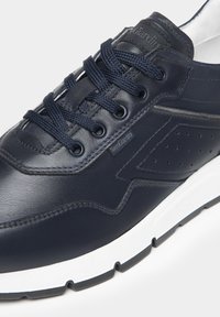 Baskets en cuir marine avec surface texturée, semelle blanche avec accents noirs, bout rond et lacets ton sur ton avec un design perforé sur le côté.