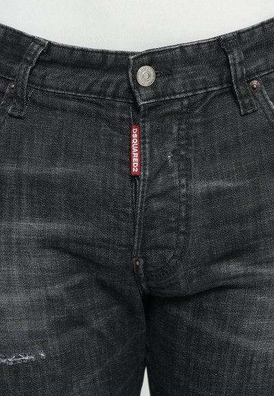 Jeans de mezclilla negros con textura desgastada, que presentan una etiqueta visible, botón metálico y diseño de cinco bolsillos. Ajuste recto clásico.