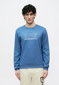 Zils garām piedurknēm džemperis ar baltu "EA7 Emporio Armani" logo, ribots apaļš kakla izgriezums un mīksts kokvilnas auduma maisījums.
