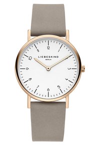 Runde Uhr mit einem weißen Zifferblatt, schlanken schwarzen Stundenmarkierungen, Gehäuse in Goldfarbe und einem weichen grauen Silikonarmband. Schlichtes, modernes Design.