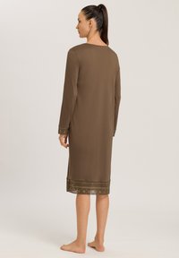 Brun långärmad nattsärk med rund halsringning och dekorativa mönstrade detaljer vid ärmslut och fåll. Slät tyg, fotlång design.