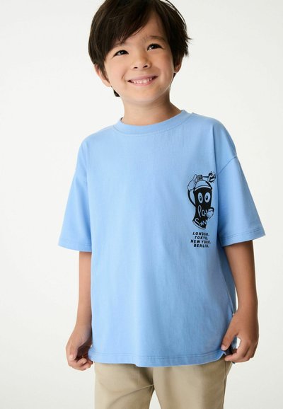 Ljusblå bomull t-shirt med korta ärmar, med en svart grafisk design på vänster bröst och text med stadnamn nedanför.