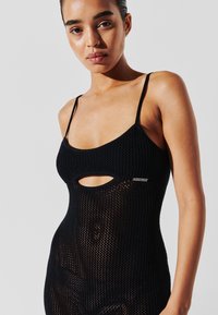 Schwarzer Strickbadeanzug mit Spaghetti-Trägern, offenen Ausschnitten und einem strukturierten Mesh-Design. Ein kleines metallisches Logo-Detail ist sichtbar.